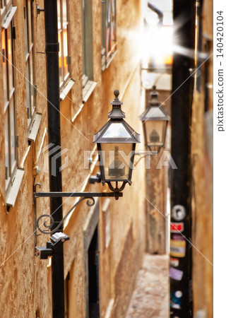 Alley, lantern and old town building for travel or cobble stone city for destination holiday, vacation or explore. Light, road and infrastructure in Italy for European trip, summer or sightseeing 140420104