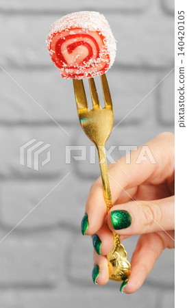 Dessert on a fork held by a hand with green nails in a casual indoor setting 140420105