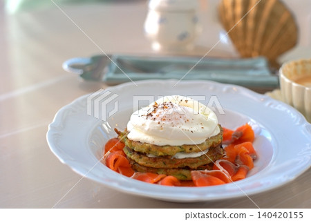 Exquisite zucchini fritters with poached eggs on a white plate. Exquisite zucchini fritters with poached eggs on a white plate. 140420155