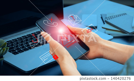 Scam call warning message on a mobile phone near a laptop and office items Scam call warning message on a mobile phone near a laptop and office items 140420276