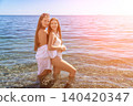 Women beach summer joy as two young friends pose in the crystal clear sea water during a sunny vacation day 140420347