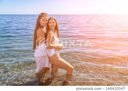 Women beach summer joy as two young friends pose in the crystal clear sea water during a sunny vacation day Women beach summer joy as two young friends pose in the crystal clear sea water during a sunny vacation day 140420347