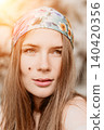 Woman headscarf portrait of a young female wearing a floral bandana outdoors during golden hour with warm light 140420356