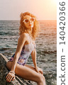 Woman swimsuit beach sitting on rocks by the ocean at sunset enjoying summer vacation 140420366