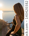 Woman bicycle sunset Young woman with bike enjoys a scenic view of the sea from a cliff at golden hour 140420382