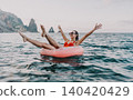 Woman, sea, vacation: Happy woman on donut inflatable in ocean, arms raised with mountain backdrop. 140420429