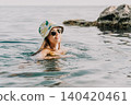 Woman, Sea, Summer: A woman wearing a bucket hat swims in the sea on a sunny day. 140420461
