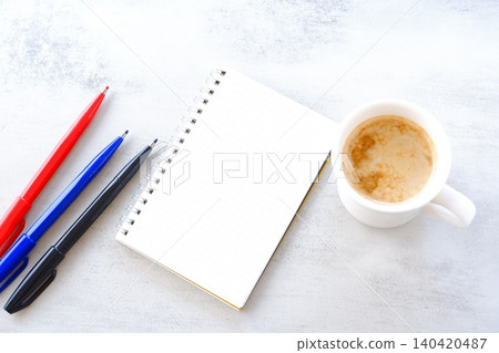 An image of working at a desk with a ring-type notepad and pen while drinking coffee. An image of working at a desk with a ring-type notepad and pen while drinking coffee. 140420487