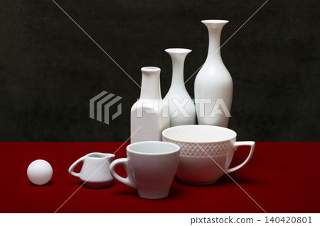 Still life with white dishes on a table with a red cover. Still life with white dishes on a table with a red cover. 140420801