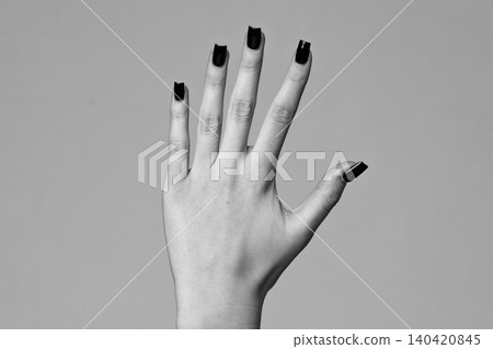 Hand with black nail polish shows fingers in close view against a plain background Hand with black nail polish shows fingers in close view against a plain background 140420845