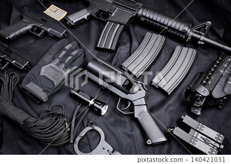 Collection of firearms and tactical gear on a black background at a gun enthusiast event Collection of firearms and tactical gear on a black background at a gun enthusiast event 140421031