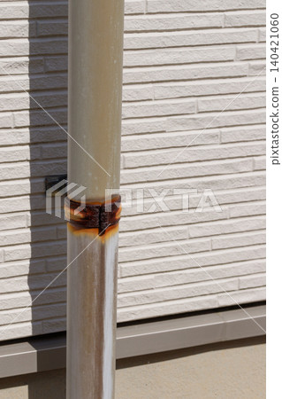 The drainpipe and fittings installed on the exterior wall of the house are rusted, causing the pipe to discolor. 140421060