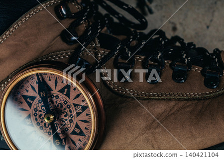 Vintage compass placed beside hiking boot on rough surface in outdoor setting 140421104