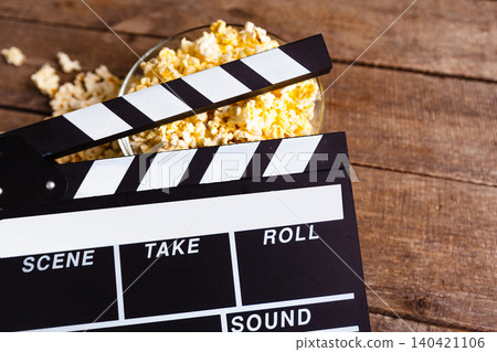 Clapperboard and popcorn on wooden table during movie night at home Clapperboard and popcorn on wooden table during movie night at home 140421106
