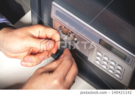 Person opens a safe using a pick tool and wire at a workspace during the day 140421142
