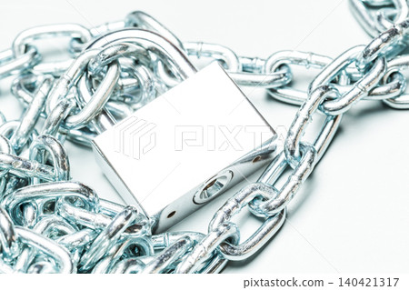 Metal lock and chain placed on a white surface showcasing security and protection measures Metal lock and chain placed on a white surface showcasing security and protection measures 140421317