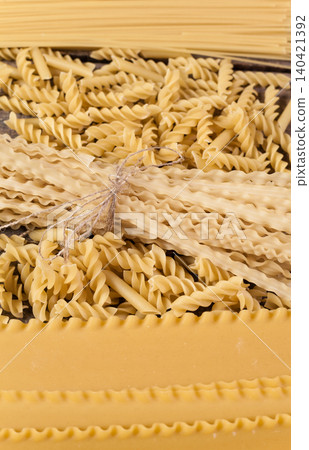 Different types of dried pasta arranged on a wooden surface in a kitchen setting Different types of dried pasta arranged on a wooden surface in a kitchen setting 140421392