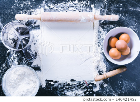 Baking process with flour, eggs, and kitchen tools on a black countertop 140421452