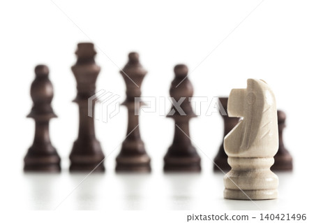Chess pieces on a board with a knight in focus during a game in a indoor setting 140421496