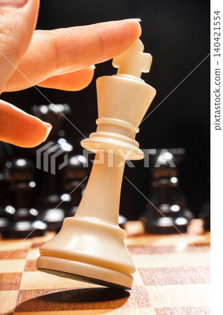 Chess piece is lifted during a game in a quiet setting at a chess table Chess piece is lifted during a game in a quiet setting at a chess table 140421554