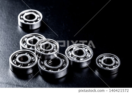 Collection of metal ball bearings on a dark surface in a workshop setting 140421572