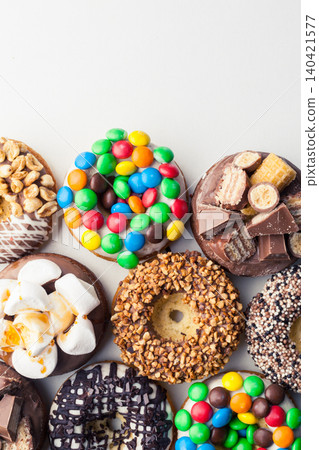 Colorful donuts with various toppings arranged on a white surface for display Colorful donuts with various toppings arranged on a white surface for display 140421577