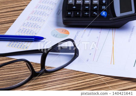 Office work involves calculations with pen, calculator, papers, and glasses on desk Office work involves calculations with pen, calculator, papers, and glasses on desk 140421641