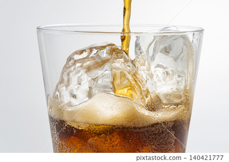 Pour cola into a glass filled with ice. Pour cola into a glass filled with ice. 140421777