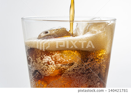 Pour cola into a glass filled with ice. Pour cola into a glass filled with ice. 140421781