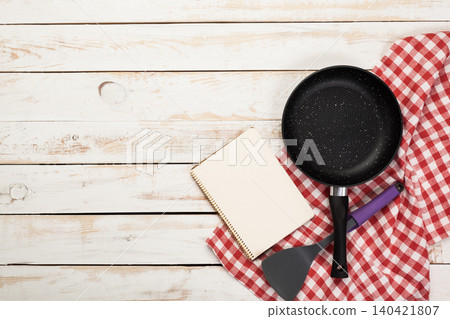 Cooking tools, a notebook, and a checkered cloth on a wooden table for meal preparation Cooking tools, a notebook, and a checkered cloth on a wooden table for meal preparation 140421807