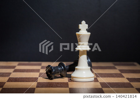 Chess game with white king standing tall next to fallen black king on board Chess game with white king standing tall next to fallen black king on board 140421814