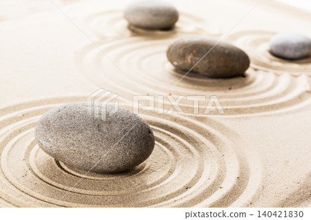 Stones placed on sand create ripples in the surface around them during a quiet moment Stones placed on sand create ripples in the surface around them during a quiet moment 140421830