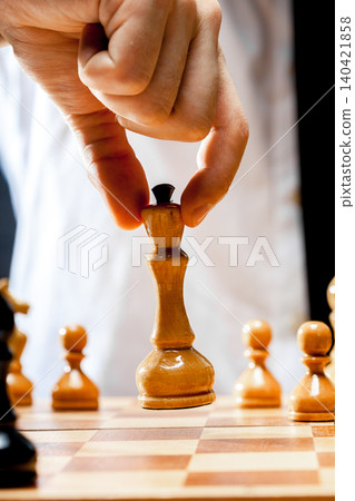 Player makes a move during a chess game with wooden pieces on a board Player makes a move during a chess game with wooden pieces on a board 140421858