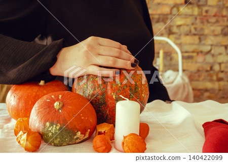 Cropped image of a woman holding a pumpkin in her hands Cropped image of a woman holding a pumpkin in her hands 140422099