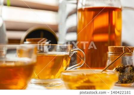 Cup of hot black tea on white table with dry tea jar Cup of hot black tea on white table with dry tea jar 140422181