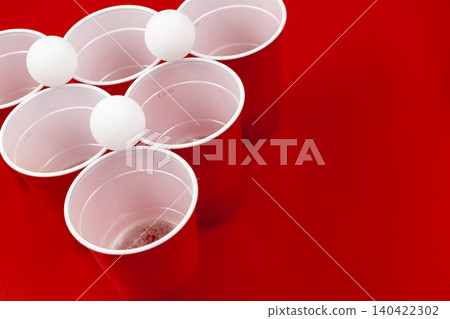 Cups and plastic ball on red background. Beer pong game Cups and plastic ball on red background. Beer pong game 140422302