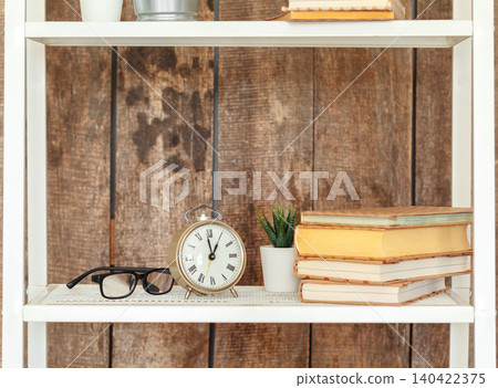 Close up of white bookshelf against grunge wooden wall Close up of white bookshelf against grunge wooden wall 140422375
