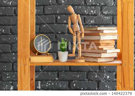Wooden bookshelf with books and stuff against black brick wall Wooden bookshelf with books and stuff against black brick wall 140422379