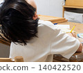 Elementary school student deep in thought while studying in the living room 140422520