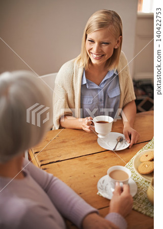 Daughter, happy woman and senior mother drinking tea at breakfast, bonding and smile. Elderly mom, adult and coffee cup at table for conversation, food and family eating cookies at home together Daughter, happy woman and senior mother drinking tea at breakfast, bonding and smile. Elderly mom, adult and coffee cup at table for conversation, food and family eating cookies at home together 140422753