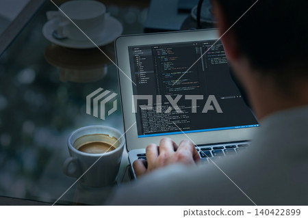 Person coding on a laptop with a cup of coffee in an office setting during the day Person coding on a laptop with a cup of coffee in an office setting during the day 140422899