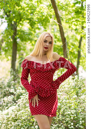 Blonde Woman in Red Dress With Hand on Hip Outdoors Blonde Woman in Red Dress With Hand on Hip Outdoors 140422996