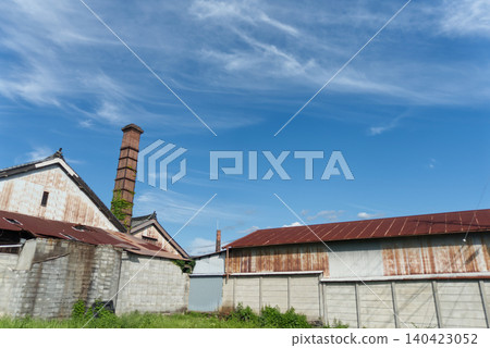 A retro scene from Shinmachi Street in Gojo City, Nara Prefecture. The brick chimney and rusty corrugated iron roof of a sake brewery stand out against the blue sky. A retro scene from Shinmachi Street in Gojo City, Nara Prefecture. The brick chimney and rusty corrugated iron roof of a sake brewery stand out against the blue sky. 140423052