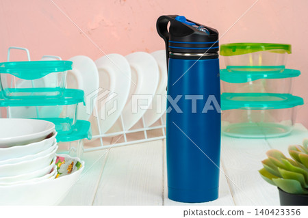 Thermos bottle against tableware in a kitchen Thermos bottle against tableware in a kitchen 140423356