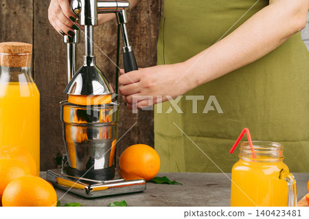 Woman using orange juicer apparatus at home Woman using orange juicer apparatus at home 140423481