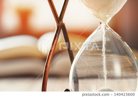 Closed up of sandglass or hourglass on background of book Closed up of sandglass or hourglass on background of book 140423600