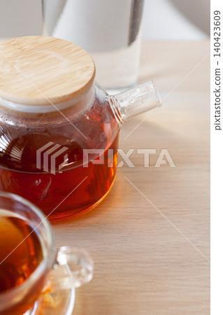 Glass tea pot with black tea on wooden table Glass tea pot with black tea on wooden table 140423609