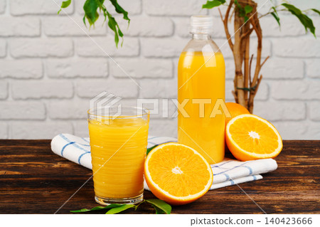 Bottle of fresh orange juice on wooden table against white brick wall background Bottle of fresh orange juice on wooden table against white brick wall background 140423666