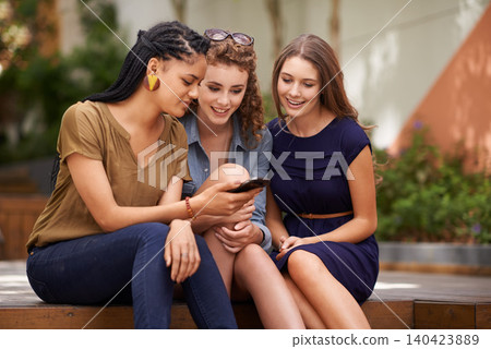 Friends, women and smile with smartphone at outdoor for social media, post and funny video. Diversity, break and memes with online entertainment on website for streaming, service for fun and happy. Friends, women and smile with smartphone at outdoor for social media, post and funny video. Diversity, break and memes with online entertainment on website for streaming, service for fun and happy. 140423889