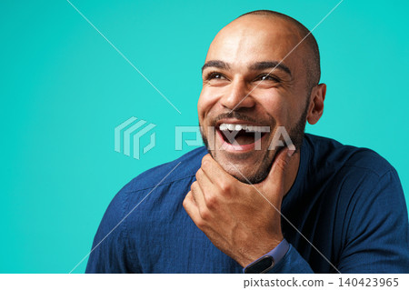 Joyful dark-skinned man laughing against turquoise background Joyful dark-skinned man laughing against turquoise background 140423965